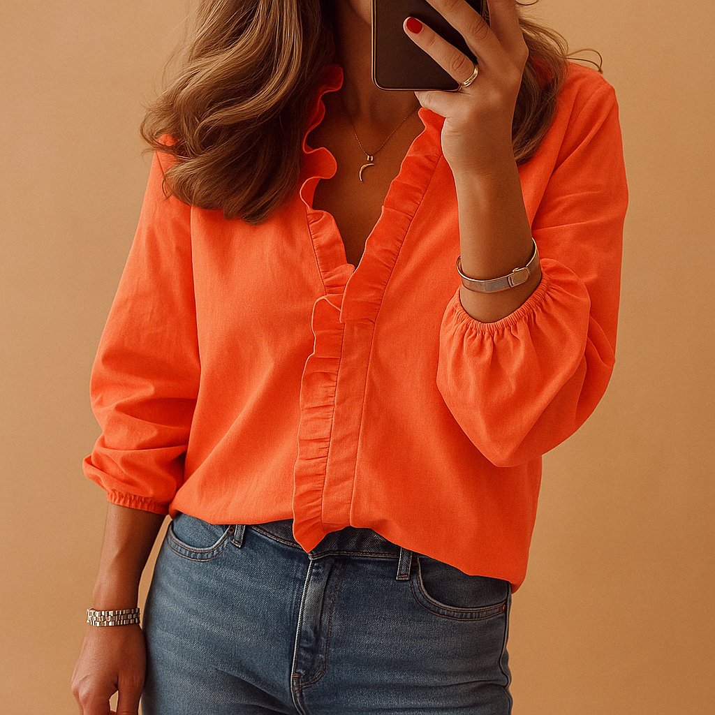 Person wearing an orange blouse and blue jeans against a brown background